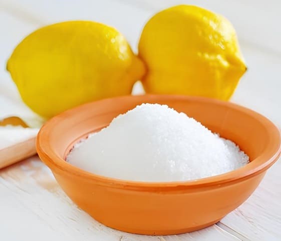 Citric Acid Powder A bowl with citric acid powder and fresh lemons is placed beside it.