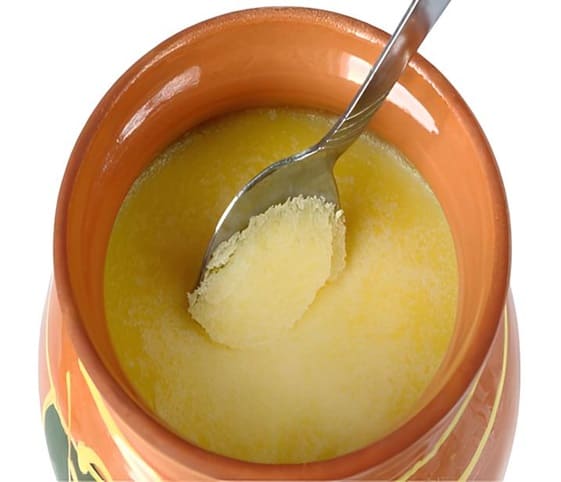 Clarified Butter A spoon is placed in a bowl of bright yellow clarified butter.