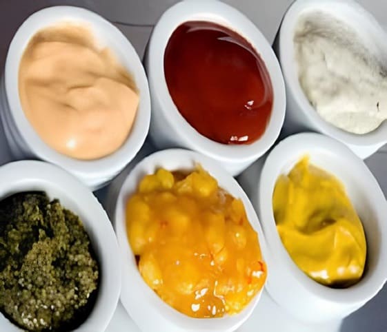 Condiments A collection of diverse sauces displayed in elegant white bowls.