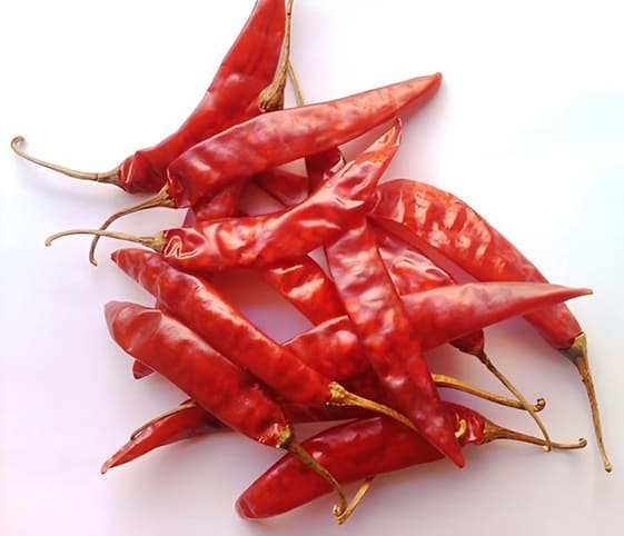Dried Red Chilli A collection of bright red chili peppers stacked on a white background.