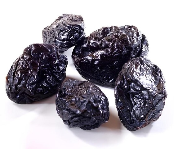 A cluster of dried prunes arranged on a clean white surface