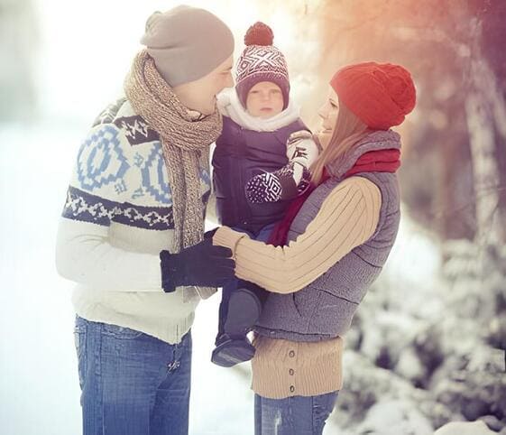 Winter Season In a snowy winter setting, a man and woman embrace a baby.